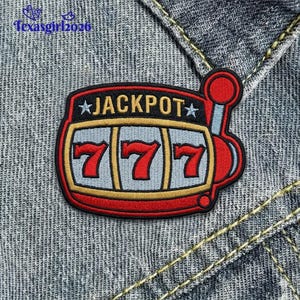 May include: Embroidered patch featuring a red, black, and gold slot machine design. The patch displays the word "JACKPOT" above three red "7" symbols. The patch is set against a denim background.