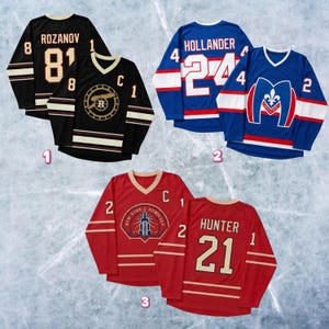 May include: A collection of hockey jerseys in black, blue, and red. Each jersey features team names, player numbers, and player names. The jerseys have white and gold accents, with the text "ROZANOV", "HOLLANDER", and "HUNTER".
