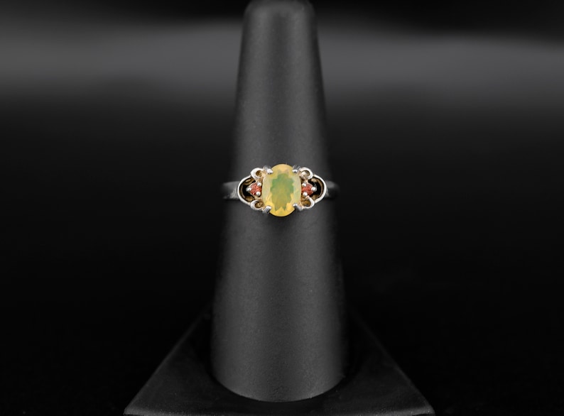 Peut inclure: Une bague en argent avec une opale ovale entour&eacute;e de petites pierres rouges.