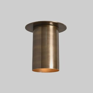 May include: A cylindrical, bronze-colored ceiling light fixture. The fixture has a circular base and a cylindrical body. The light is on, and the interior of the cylinder is illuminated with a warm glow. The fixture is designed for indoor use.
