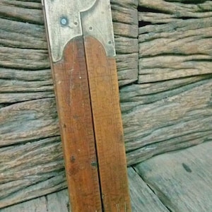 May include: A vintage wooden folding ruler with brass fittings. The ruler is a warm brown colour, with visible measurement markings. The brass components show signs of age and wear. The ruler is partially open, revealing its folding mechanism.