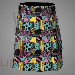 May include: A kilt featuring a patchwork design with a repeating pattern of black, yellow, light blue, and pink geometric shapes. The fabric displays various textures including polka dots, stripes, and swirls, with a structured waistband and pleats.