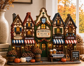 May include: A miniature Oktoberfest village display featuring five connected timber-framed buildings with illuminated windows. The center sign reads OKTOBERFEST VILLAGE EAT DRINK BE MERRY. Includes miniature beer mugs, pretzels, pumpkins, and a sign stating GOOD FRIENDS COLD BEER GREAT TIMES.