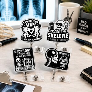 Peut inclure: Quatre enrouleurs de badge en acrylique avec des graphismes médicaux en noir et blanc. Les motifs incluent un squelette faisant un selfie, un bassin avec du texte, un panneau de radiologie avec un squelette et un crâne avec du texte.