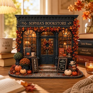Peut inclure: Une maquette de librairie miniature intitulée Sophia's Bookstore avec un extérieur bleu foncé, des fenêtres arquées et un éclairage intérieur. La façade est décorée de feuilles d'automne orange, de citrouilles et de panneaux Read et New Arrivals.