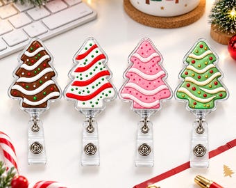May include: Four retractable badge reels shaped like Christmas trees, each featuring a different color scheme: brown, white with red, pink, and green. Each tree is decorated with wavy lines and small dots, attached to a clear plastic clip.