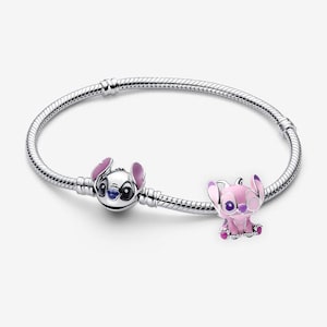 May include: A silver charm bracelet with two Disney-themed charms. One charm is a silver Stitch head with pink ears, and the other is a pink Angel charm. The bracelet is on a white background.