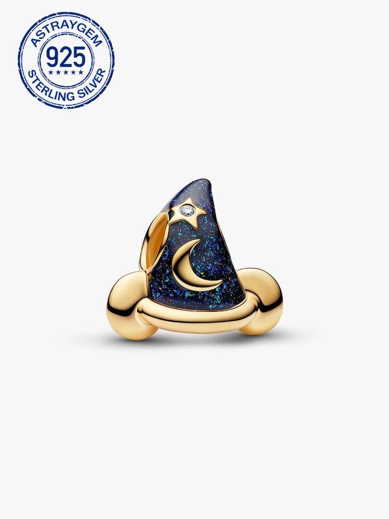 K&ouml;nnte beinhalten: Ein goldfarbener Charm in Form eines Zaubererhuts. Der Hut ist dunkelblau mit einem Sternenmuster und einem Mond. Ein kleiner klarer Edelstein ist auf dem Hut gesetzt. Der Charm hat ein goldenes Band und ist mit "925 STERLING SILVER" markiert.