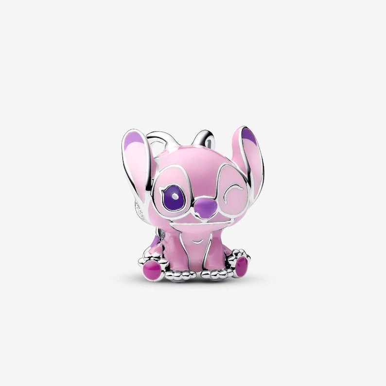 May include: A pink and silver charm featuring a cartoon character with large ears, a winking eye, and purple accents. The charm is detailed with silver outlines and a glossy finish, showcasing a playful design.