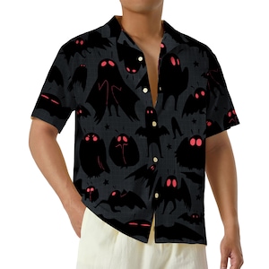 May include: A short-sleeve button-down shirt in dark gray featuring an all-over pattern of black moth-like creatures with glowing red eyes. The shirt has a classic collar, a front button placket with light-colored buttons, and a straight hemline.
