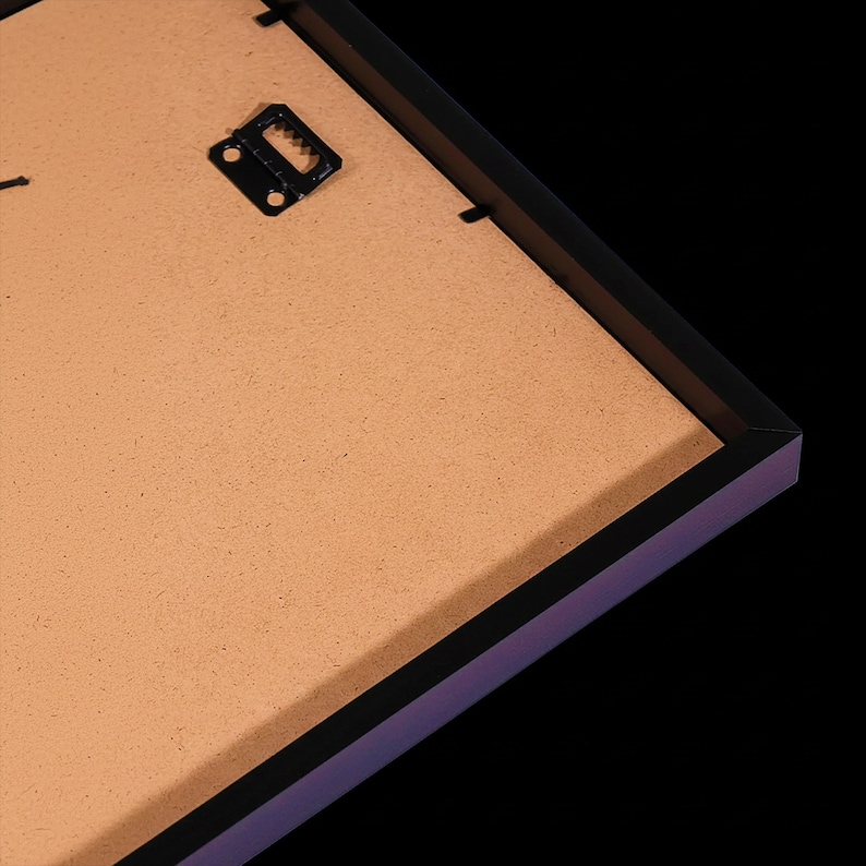 a close-up view of a wooden frame with a black metal hook or bracket attached to it, set against a dark background.