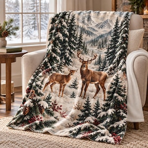 Könnte beinhalten: Eine weiche Wohndecke mit einer Winterlandschaft, die zwei Hirsche in einem verschneiten Wald zeigt. Das Motiv umfasst schneebedeckte Tannen, rote Beeren, Tannenzapfen und ferne Berge unter einem hellen Himmel, gedruckt auf einem weichen Stoff.