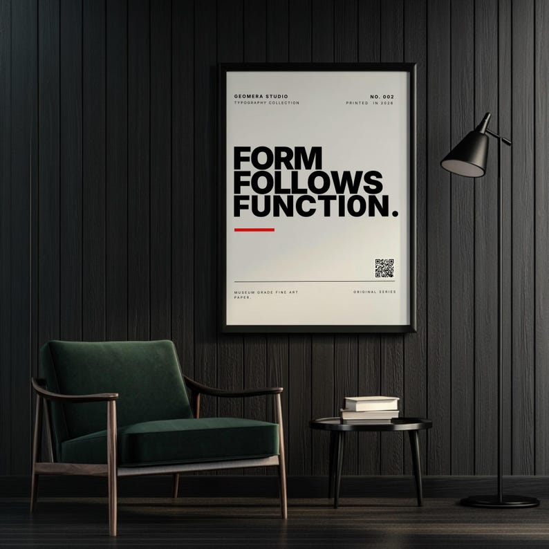 "Form Follows Function" minimalist typography wall art physical print by GEOMERA. Framed quote poster featuring bold black text, a red accent line, and a storytelling QR code. Moody modern home decor displayed on a dark wood-paneled wall next to a dark green velvet armchair and a black floor lamp.