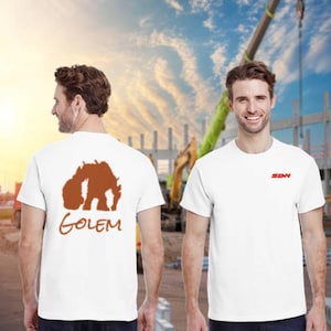 May include: White t-shirts with short sleeves. One shirt has a brown graphic of a creature and the word "GOLEM" in brown. The other shirt has the red letters "SDN" on the chest. The background shows construction equipment and a blue sky.