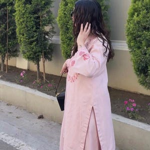 May include: A light pink two-piece outfit with floral embroidery. The long-sleeved top and matching pants feature decorative floral patterns. The outfit is worn with a black purse. The brand name "ZiyaFab" is visible in the top right corner.
