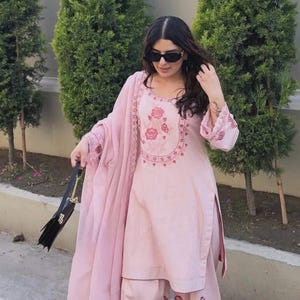 May include: A light pink embroidered salwar kameez set with matching palazzo pants and a dupatta. The top features floral embroidery around the neckline and on the sleeves. The palazzo pants have floral embroidery. The image includes the text "ZiyaFab".