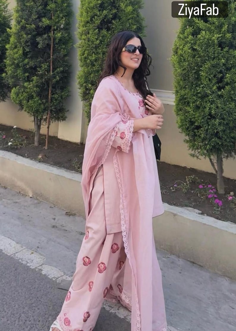 May include: A light pink salwar kameez set. The outfit includes a tunic, pants, and a scarf. The tunic and pants feature floral embroidery. The set is made of a lightweight fabric. The brand name "ZiyaFab" is visible in the top right corner.