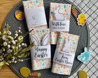 Puede incluir: Cuatro servilletas decorativas con temática de Pascua con bandas de papel blanco con siluetas de conejos y saludos festivos. Las servilletas tienen un patrón colorido de huevos y flores. Decoraciones de Pascua.