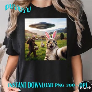 May include: Black t-shirt featuring a colorful graphic of a cat taking a selfie with bunny ears, a Bigfoot, a UFO, and a bunny in a field. The text "INSTANT DOWNLOAD PNG 300 - DPI Black" is at the bottom.