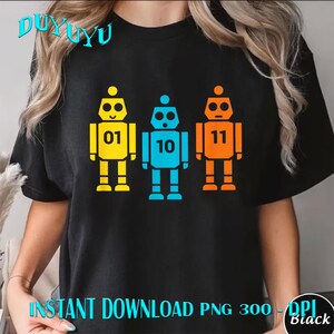 Pode incluir: Camiseta preta com três ilustrações de robôs coloridos. Os robôs são amarelos, azuis e laranjas, cada um com um número diferente: 01, 10 e 11. O texto "INSTANT DOWNLOAD PNG 300 - DPI Black" está na parte inferior.