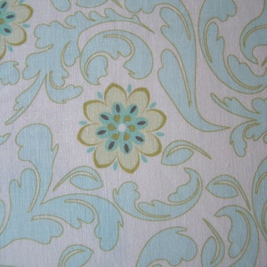 Könnte beinhalten: Nahaufnahme eines Stoffes mit einem sich wiederholenden Blumen- und Scrollmuster. Das Design zeigt hellblaue und olivgrüne Blumen und wirbelnde Blattformen auf weißem Hintergrund. Der Stoff hat ein strukturiertes Aussehen.