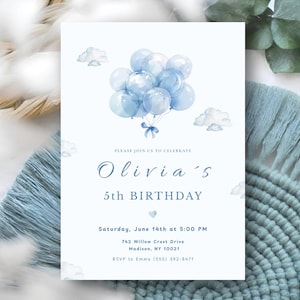 Puede incluir: Una tarjeta de invitación blanca con una ilustración de acuarela de globos y nubes azules. El texto dice "Olivia's 5th BIRTHDAY" con los detalles del evento. La tarjeta está sobre un fondo texturizado con macramé azul.