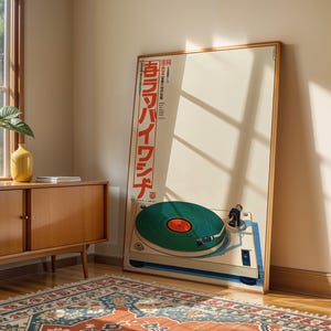 May include: A framed poster featuring a vintage turntable with a green record. The poster has Japanese text in red and is leaning against a wall. A wooden cabinet with a plant and a yellow vase sits nearby.
