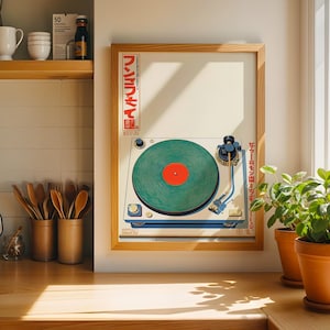 May include: A framed print of a vintage turntable with a green record and red center label. The print has Japanese text and is in a light wood frame. The image is displayed on a wooden countertop with potted plants nearby.