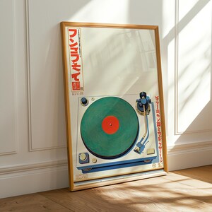May include: A framed poster featuring a vintage turntable design. The turntable has a green record with a red center, set against a cream background. Japanese text is visible on the frame. The frame is a light brown color.