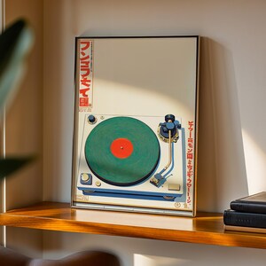 May include: A framed print of a vintage turntable with a green record and red center label. The artwork features Japanese text in red and a cream-colored background. The turntable is white and blue, with gold accents.