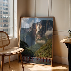 May include: A framed print of Angel Falls, showing a waterfall cascading through a verdant landscape with high rock formations. The print is in a wooden frame and has the text "ANGEL FALLS" in red.