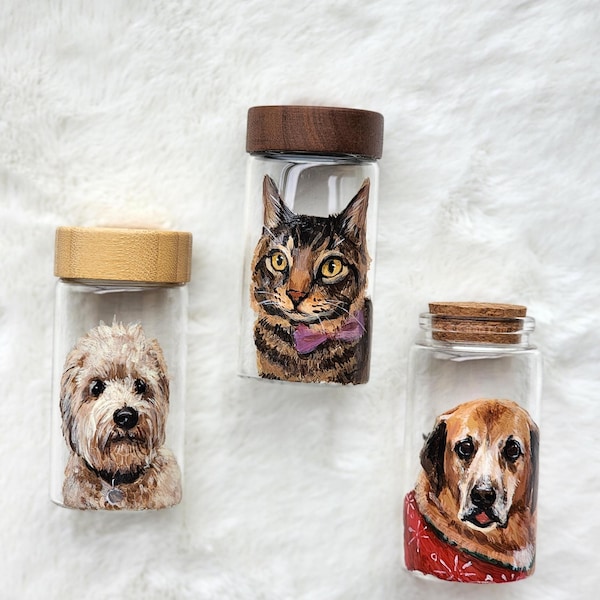 May include: Three clear glass jars with wooden lids, each featuring a hand-painted portrait of a pet. One jar shows a fluffy tan dog, another a brown tabby cat with a purple bow tie, and the third a golden-brown dog wearing a red patterned sweater.