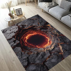 May include: A rectangular area rug with a striking design resembling a volcanic crater. The rug features a dark gray, textured surface with a central, circular design in shades of orange and black, creating a dramatic visual effect. The rug is designed for indoor use.