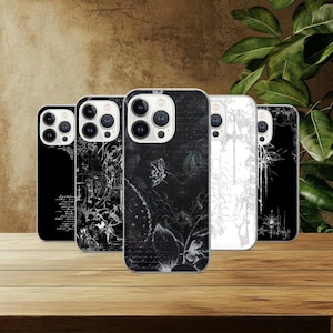 May include: A collection of five phone cases with unique designs. The cases feature black and white graphics, including floral patterns, abstract art, and script. The cases are displayed on a wooden surface with a neutral background.