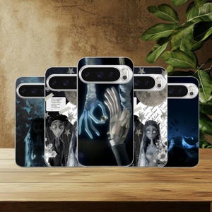 Puede incluir: Un conjunto de fundas para teléfono con ilustraciones de una película de animación stop-motion. Las fundas muestran personajes, manos y una luna sobre un fondo oscuro. Las fundas están dispuestas sobre una superficie de madera.