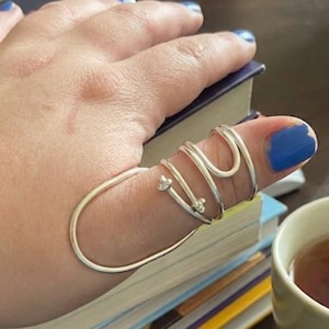 May include: A white ceramic mug with a black handle and the text "But First, Coffee" in a bold, black font. The mug is set against a blurred background, suggesting a cozy setting.