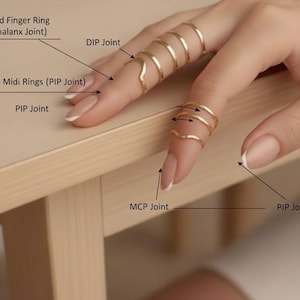 Könnte beinhalten: Nahaufnahme einer Hand mit mehreren goldfarbenen Ringen, darunter gebogene Fingerringe und stapelbare Midi-Ringe. Der Text zeigt die Fingergelenke. Ein stilvolles Accessoire.