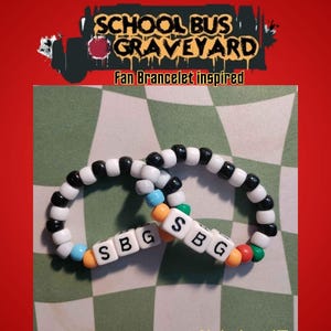 May include: Two beaded bracelets with black, white, and colorful beads. The bracelets have the letters "SBG" on them. The image also includes the text "SCHOOL BUS GRAVEYARD" and "Fan Bracelet inspired" and "Limited stock!!!".