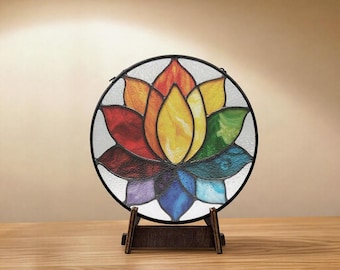 Peut inclure: Un vitrail rond représentant une fleur de lotus aux pétales multicolores : rouge, orange, jaune, vert, bleu et violet. Le verre est encadré de métal noir et présenté sur un support en bois, idéal pour la décoration intérieure.