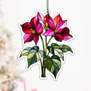May include: A stained glass floral decoration featuring vibrant red and pink flowers with yellow centers, green stems, and variegated green and white leaves. The decorative piece is suspended by a silver chain, perfect for adding a touch of color to any space.