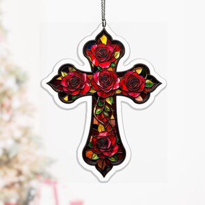 Könnte beinhalten: Ein dekoratives Kreuz mit einem Buntglas-Design, verziert mit roten Rosen und grünen Blättern. Das Kreuz ist schwarz-weiß umrandet und hat eine Kette zum Aufhängen. Die Rosen blühen voll, was dem religiösen Symbol Eleganz verleiht.