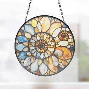 Peut inclure: Un capteur de soleil circulaire en vitrail présentant un motif complexe en mosaïque de pièces de verre jaunes, orange, bleues et blanches disposées en spirale d'ammonite, assemblées par des joints en métal sombre et suspendu par une chaîne noire.