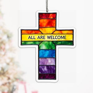 May include: A stained glass cross ornament with a rainbow color scheme. The cross features the text "ALL ARE WELCOME" in yellow. The ornament is hanging from a silver chain.