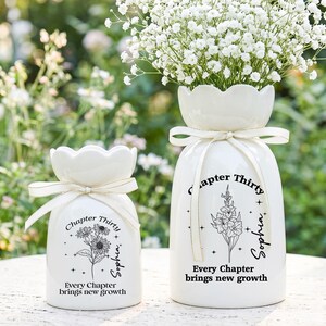 May include: Two white ceramic vases with scalloped rims and cream-colored ribbons. Each vase features black text reading Chapter Thirty, the name Sophia, and the phrase Every Chapter brings new growth, accompanied by floral line art illustrations.