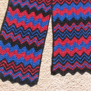 May include: A black, red and blue knitted scarf with a chevron pattern.
