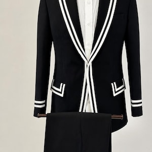 Könnte beinhalten: Ein schwarzer Anzug mit einem weißen Hemd und einer schwarzen Fliege. Der Blazer hat weiße Paspeln an den Revers, den Taschenklappen und den Ärmelabschlüssen. Der Text PeaceloveandjoyArt ist in der oberen linken Ecke des Bildes zu sehen.