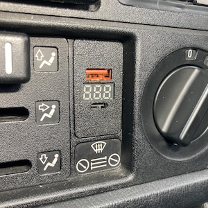 Könnte beinhalten: Nahaufnahme eines schwarzen Armaturenbretts mit Klimaanlagen-Bedienelementen. Enthält eine Digitalanzeige mit der Anzeige "888", einen Lüfterdrehzahlregler und verschiedene Steuertasten mit Symbolen.