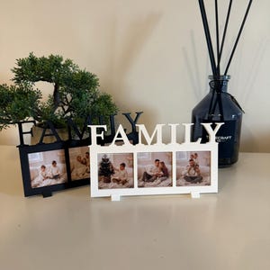 Puede incluir: Dos marcos de fotos con la palabra "FAMILY". Un marco negro, el otro blanco, cada uno con tres fotos. Un difusor de vidrio azul oscuro con varillas negras en el fondo.
