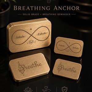 Four rectangular solid brass breathing anchor tokens in different sizes and designs displayed on a black reflective surface.