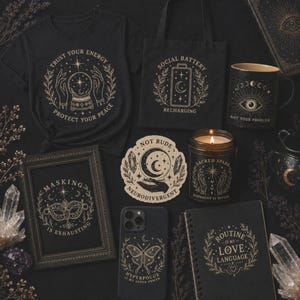 A flat lay of various witchy-themed products on a dark background, including a black t-shirt, a tote bag, a mug, a framed print, a phone case, a candle, and a notebook.